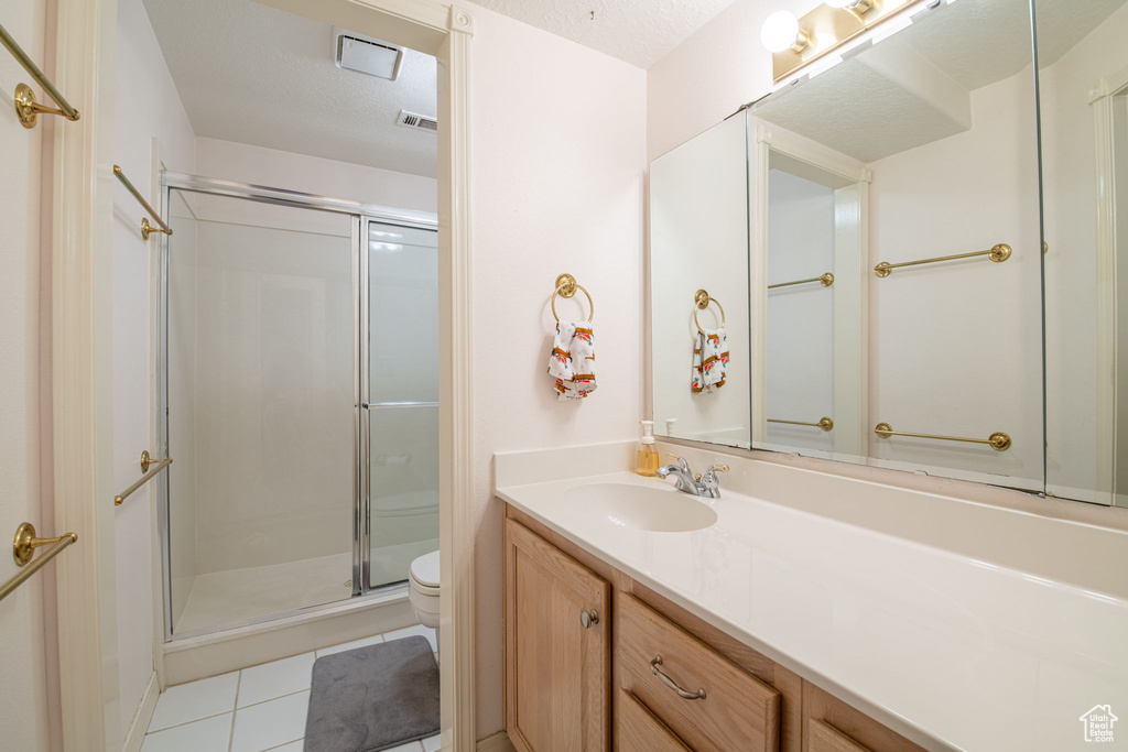 Bathroom with toilet, a shower stall, tile patterned floors, and vanity