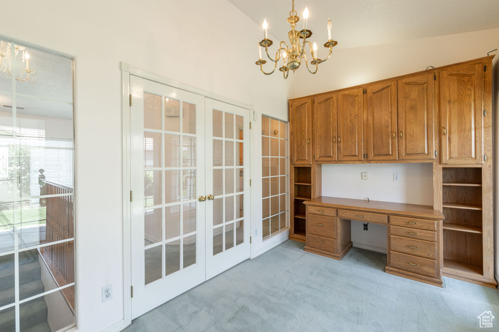 Unfurnished office with a chandelier, french doors, light carpet, built in study area, and high vaulted ceiling