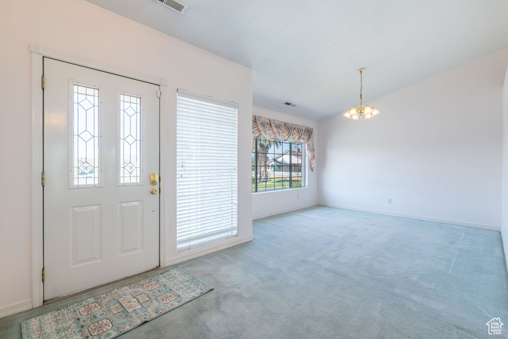 Foyer featuring a chandelier, carpet flooring, and baseboards