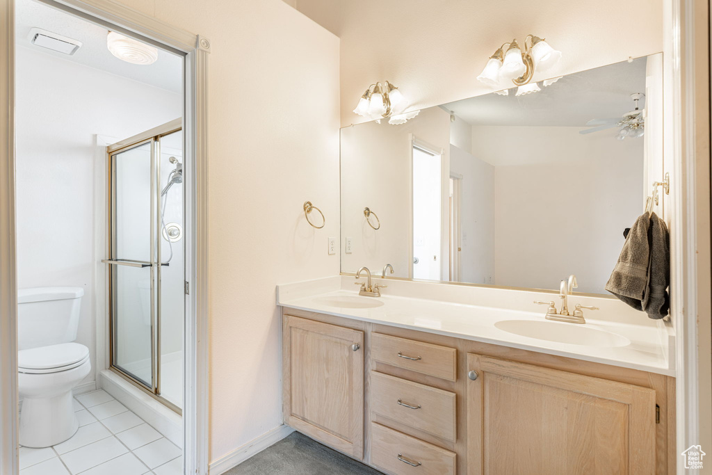 Bathroom featuring toilet, a shower stall, double vanity, and tile patterned flooring