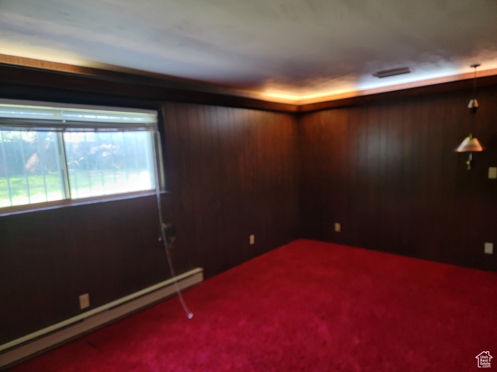 Unfurnished room with a baseboard radiator, carpet, and wood walls