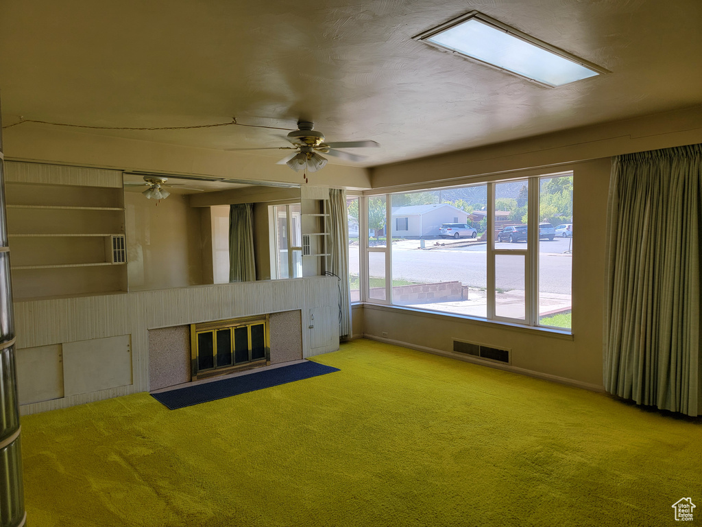 Unfurnished living room featuring a fireplace with flush hearth, carpet, ceiling fan, and baseboards