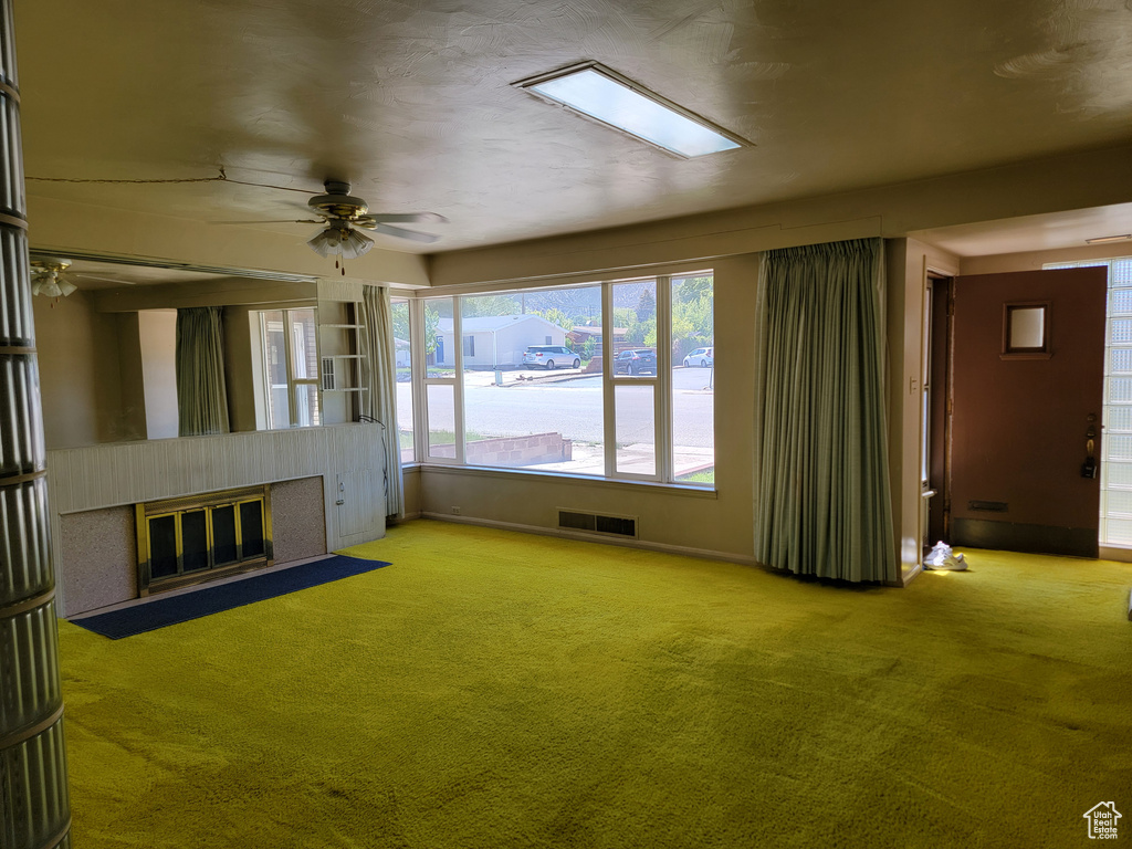 Unfurnished living room featuring a fireplace with flush hearth, a ceiling fan, carpet floors, and baseboards