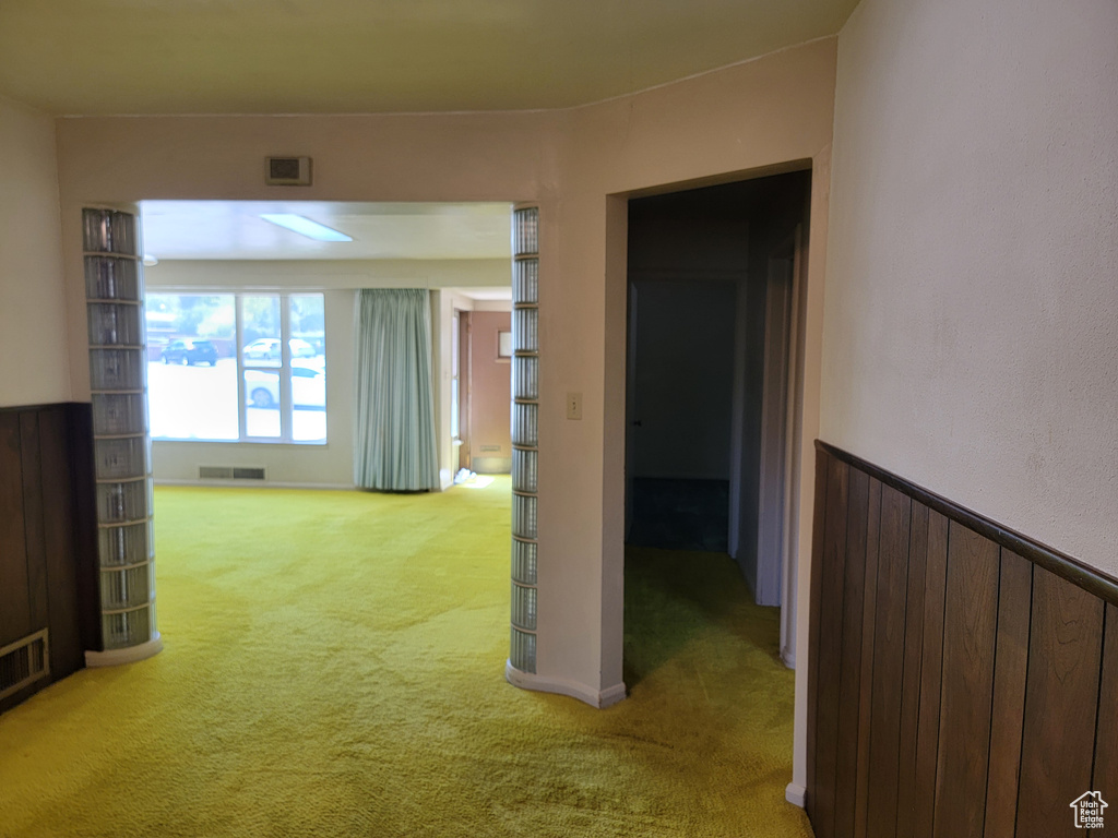 Corridor featuring light colored carpet and wainscoting