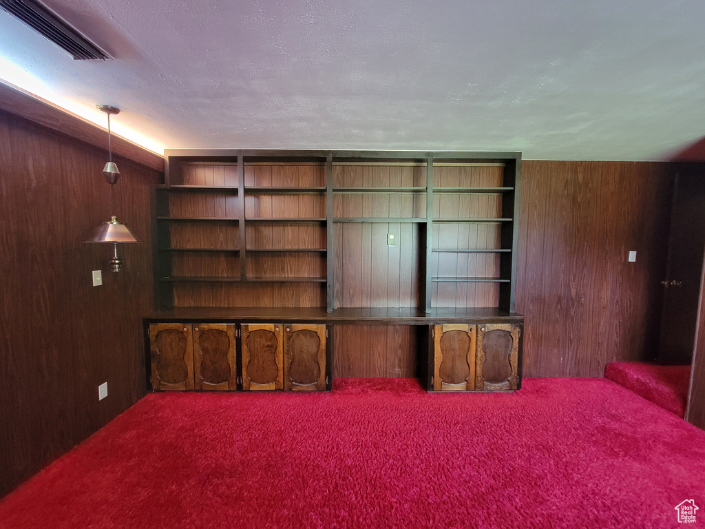 Unfurnished living room featuring wood walls