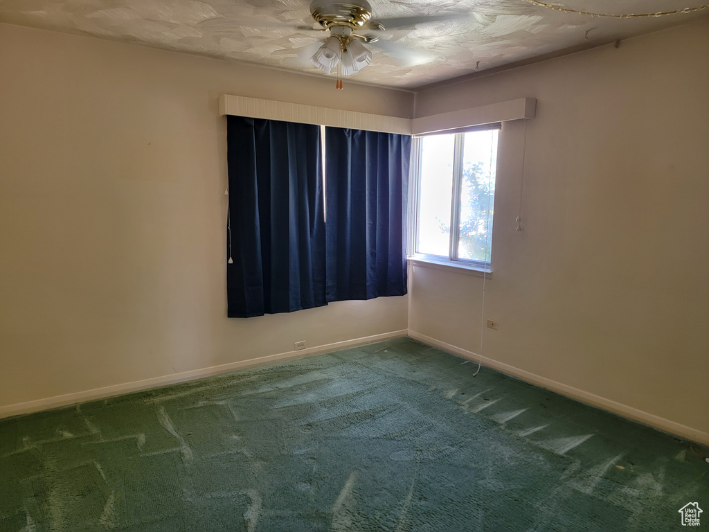 Carpeted empty room with a ceiling fan and baseboards