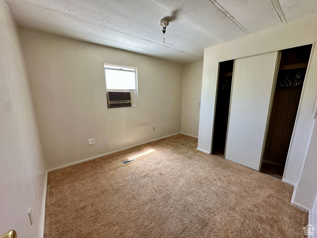 Unfurnished bedroom with carpet, a closet, and a textured ceiling