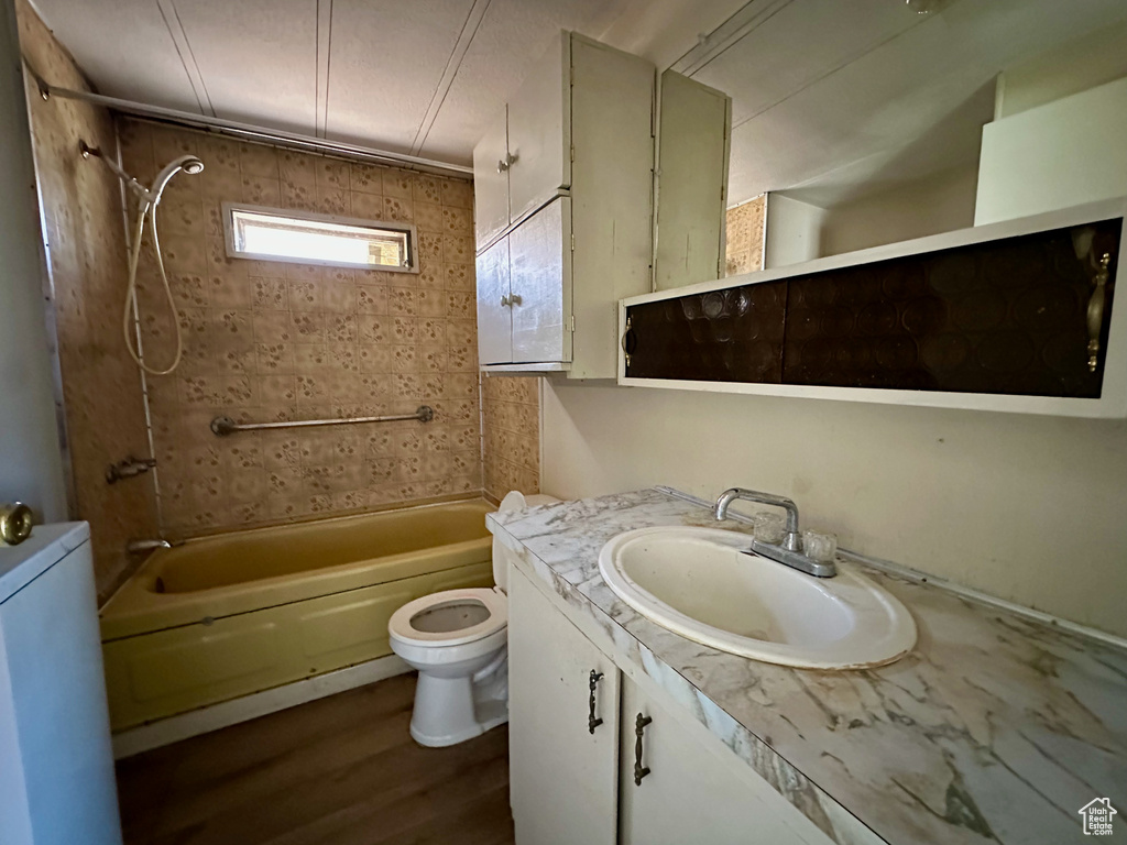 Bathroom featuring toilet, tub / shower combination, wood finished floors, and vanity