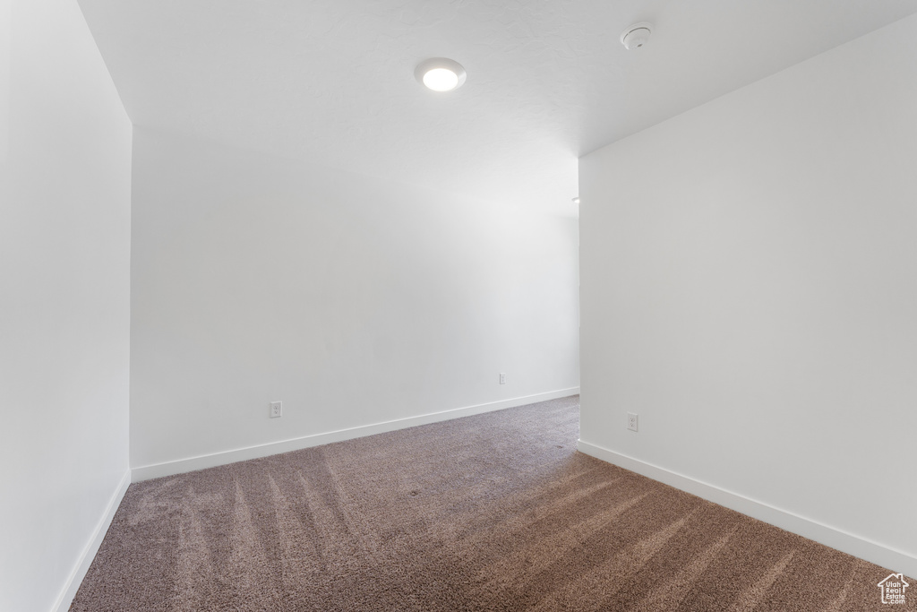 Unfurnished room featuring carpet, baseboards, and a smoke detector