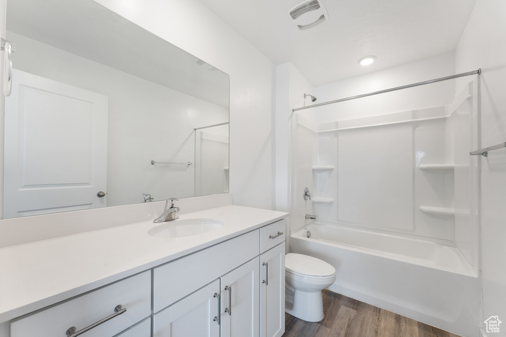 Full bath with toilet, wood finished floors, vanity, and  shower combination