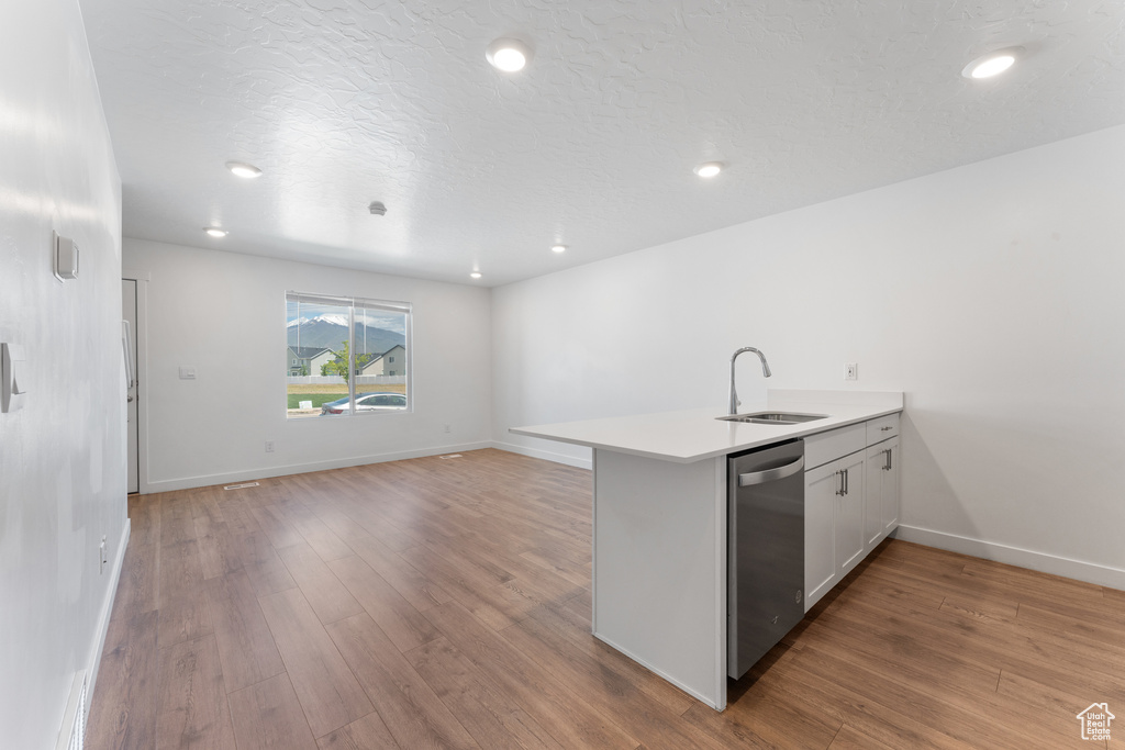 Kitchen featuring dishwasher, a sink, a peninsula, light wood-style flooring, and open floor plan