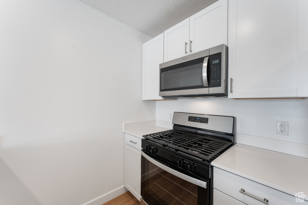 Kitchen featuring appliances with stainless steel finishes, light countertops, and white cabinets