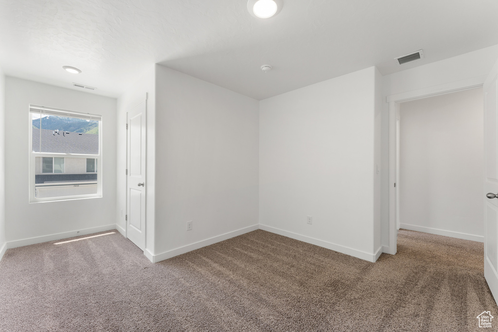 Carpeted spare room featuring baseboards