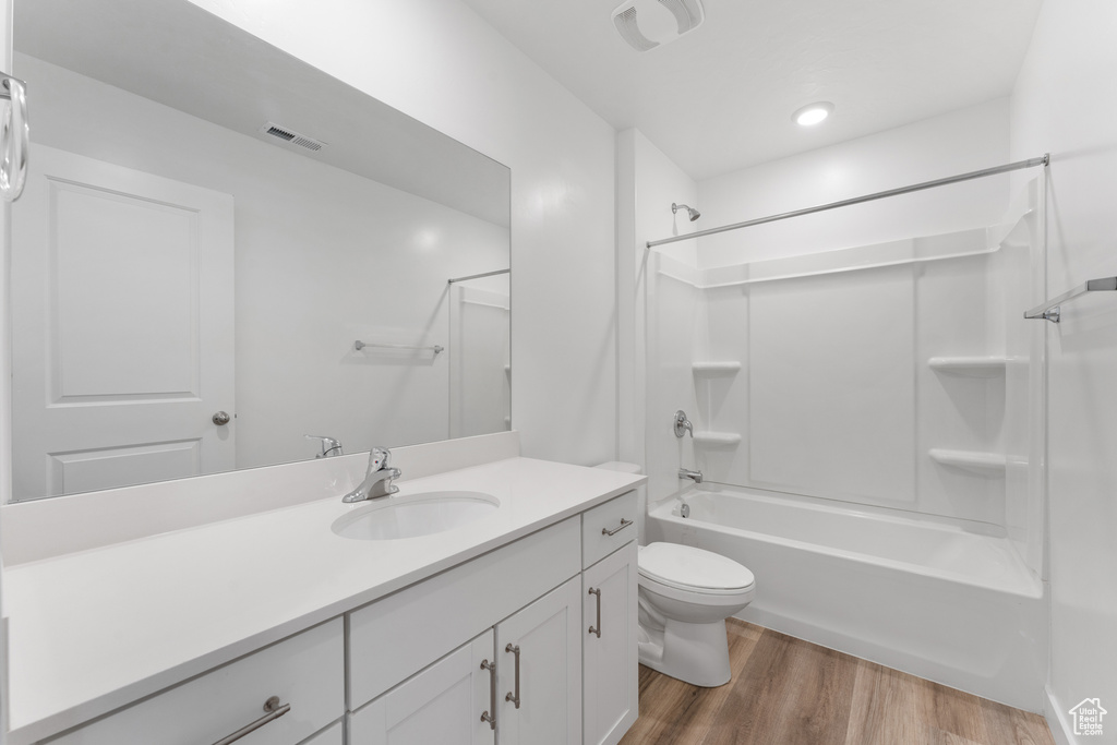 Full bath with wood finished floors, toilet, vanity, and bathing tub / shower combination