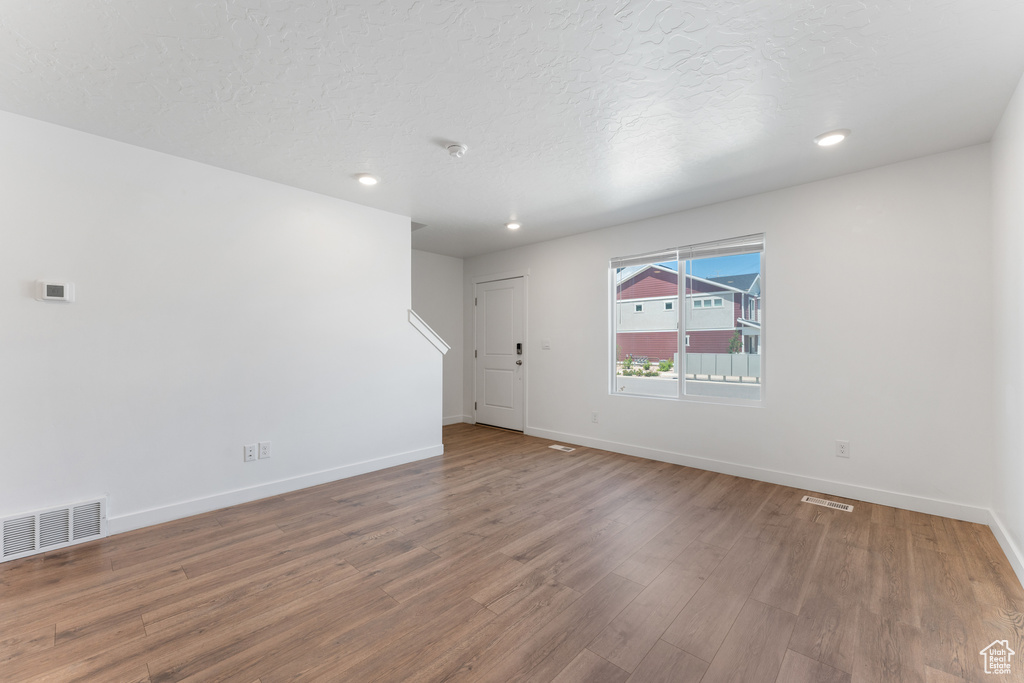 Spare room featuring wood finished floors, baseboards, recessed lighting, and a textured ceiling