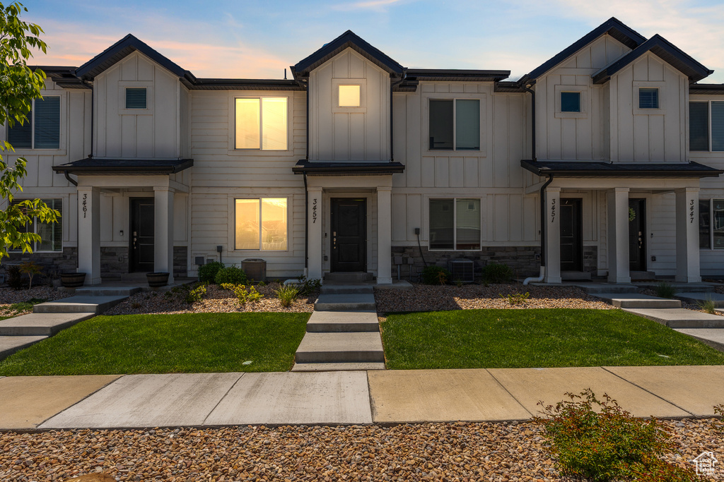 View of front facade featuring board and batten siding, stone siding, and a lawn