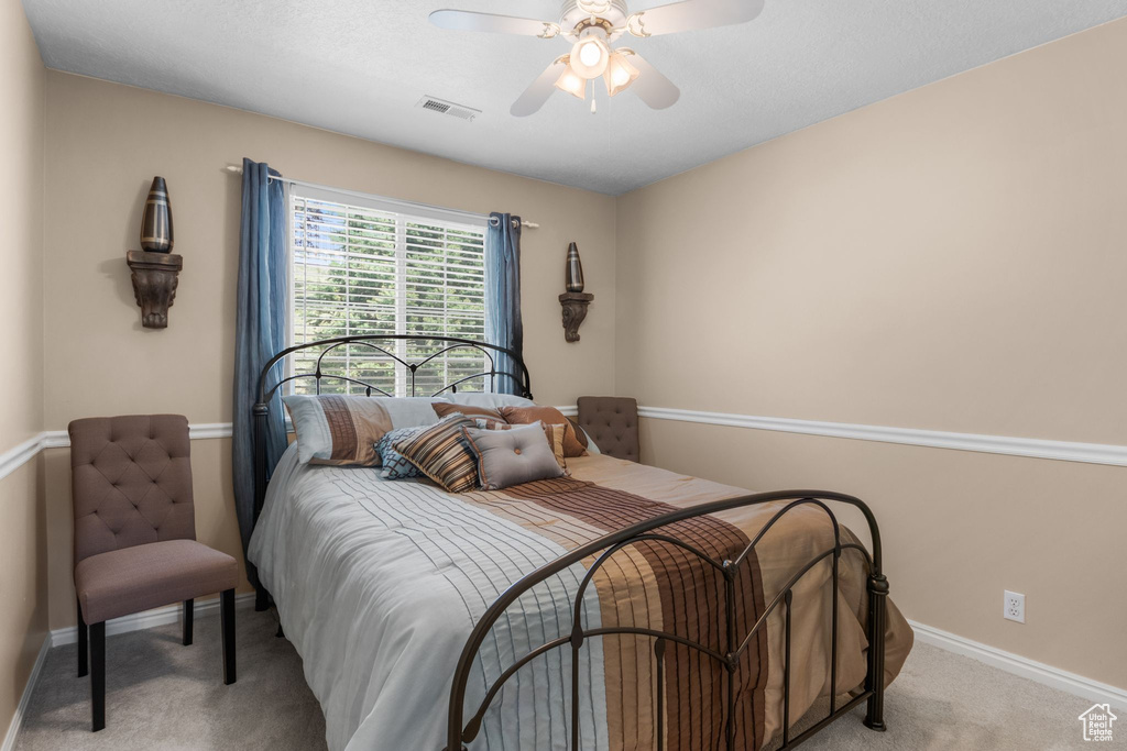 Bedroom with light carpet, baseboards, and a ceiling fan