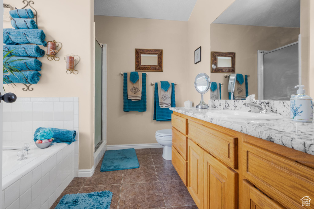 Full bath featuring a stall shower, baseboards, tile patterned floors, vanity, and toilet