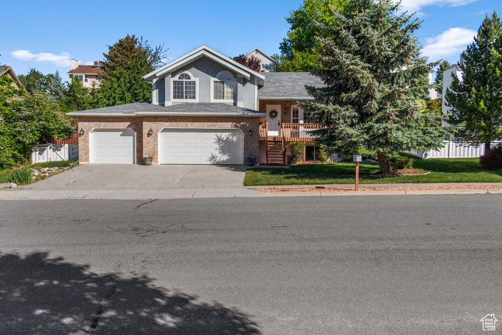 Split level home with concrete driveway, an attached garage, brick siding, and stairs