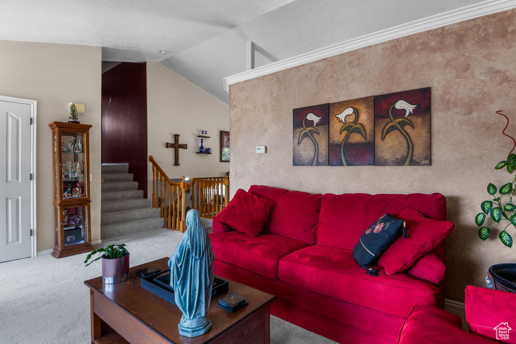 Carpeted living room featuring vaulted ceiling, stairs, and baseboards