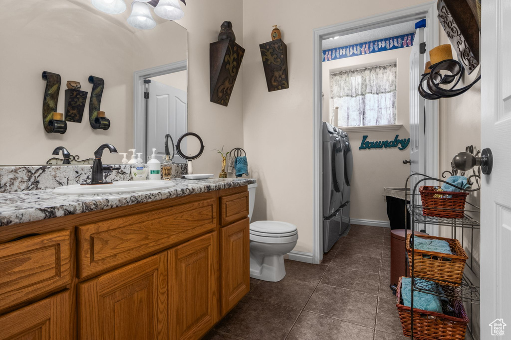 Bathroom with tile patterned floors, toilet, vanity, and washer / clothes dryer