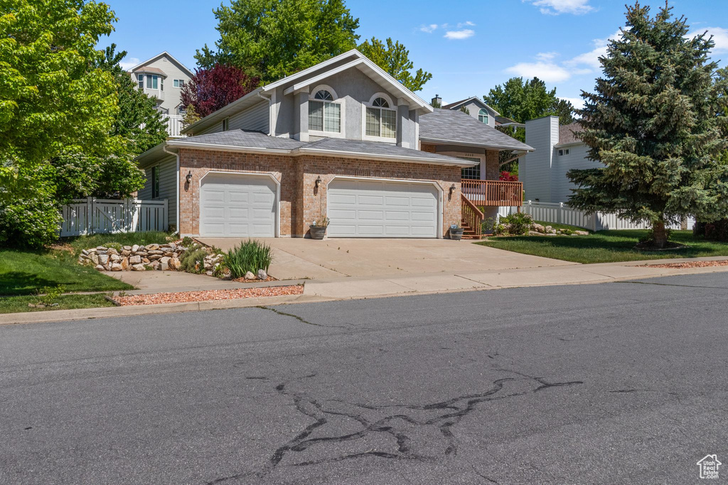 Traditional-style home with brick siding, concrete driveway, an attached garage, and stairway