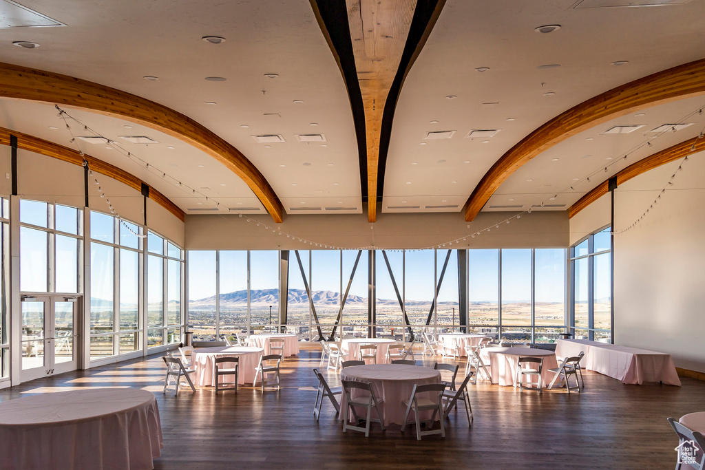 Dining room featuring a mountain view, beam ceiling, wood finished floors, plenty of natural light, and expansive windows