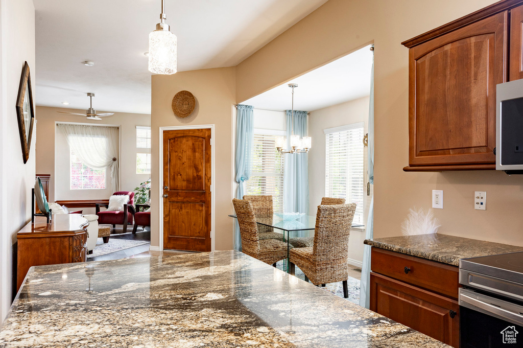 Kitchen with stainless steel electric range, plenty of natural light, a chandelier, and brown cabinets