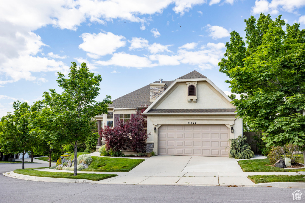 View of front of house featuring stucco siding, concrete driveway, a garage, a chimney, and roof with shingles