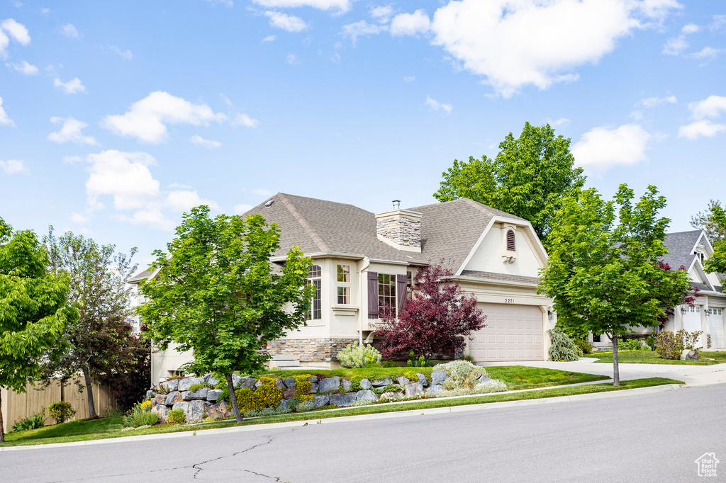 French country style house with concrete driveway, a shingled roof, stucco siding, a chimney, and stone siding