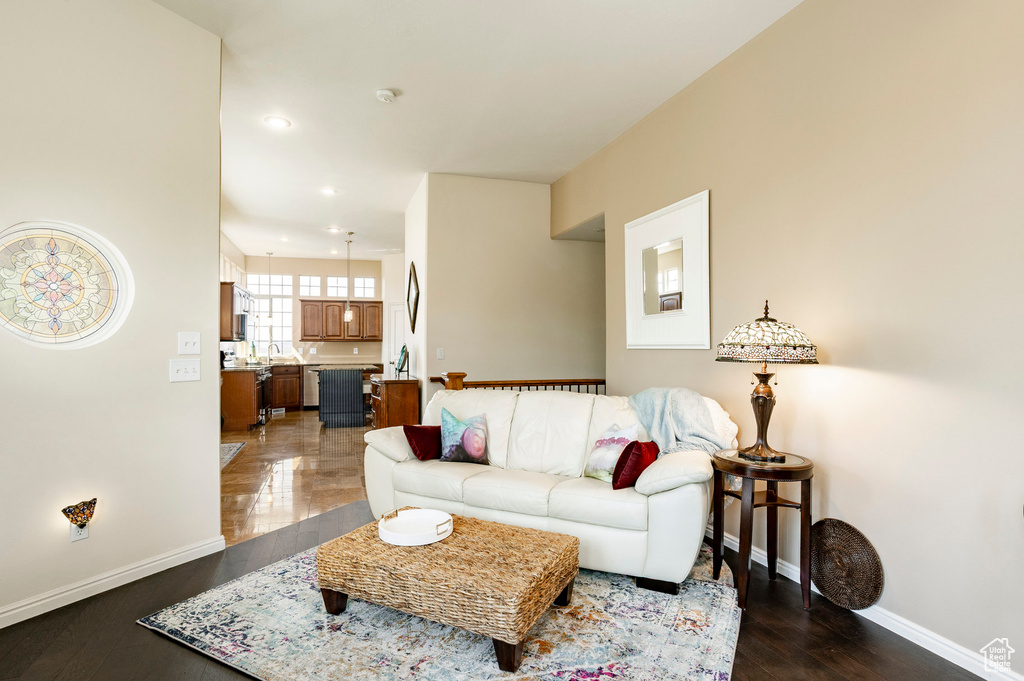 Living area with dark wood-style flooring, baseboards, and recessed lighting
