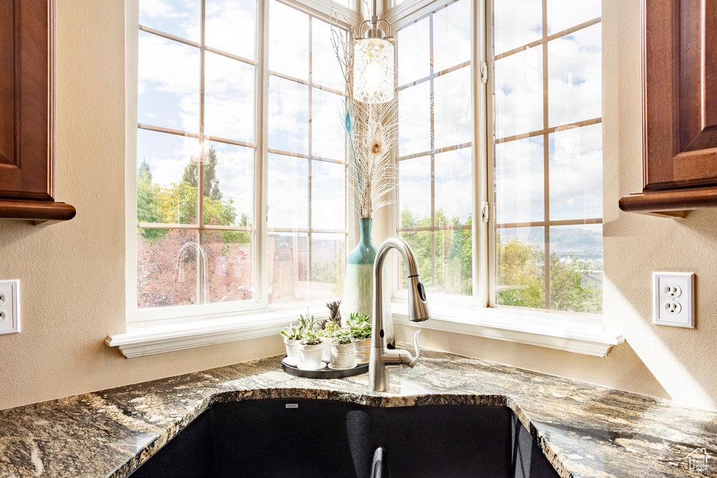Kitchen view of a textured wall, a sink, and dark stone counters
