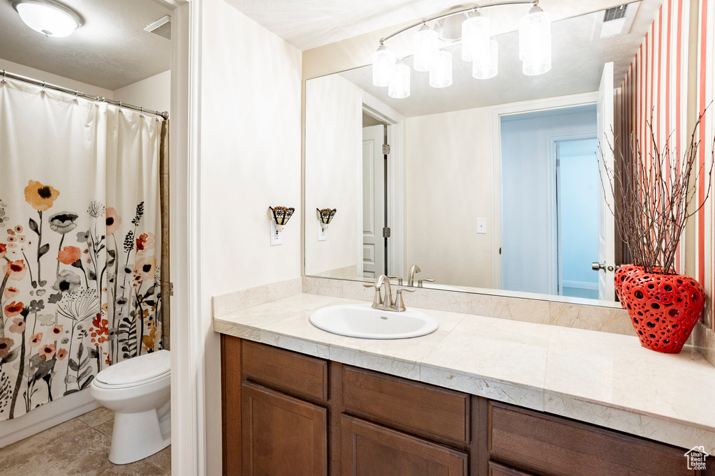 Full bath with toilet, vanity, tile patterned floors, and curtained shower