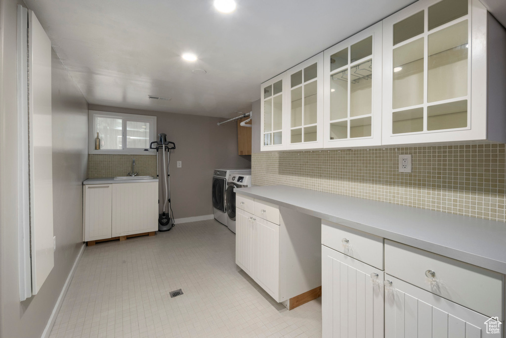 Kitchen with separate washer and dryer, decorative backsplash, baseboards, light countertops, and glass insert cabinets