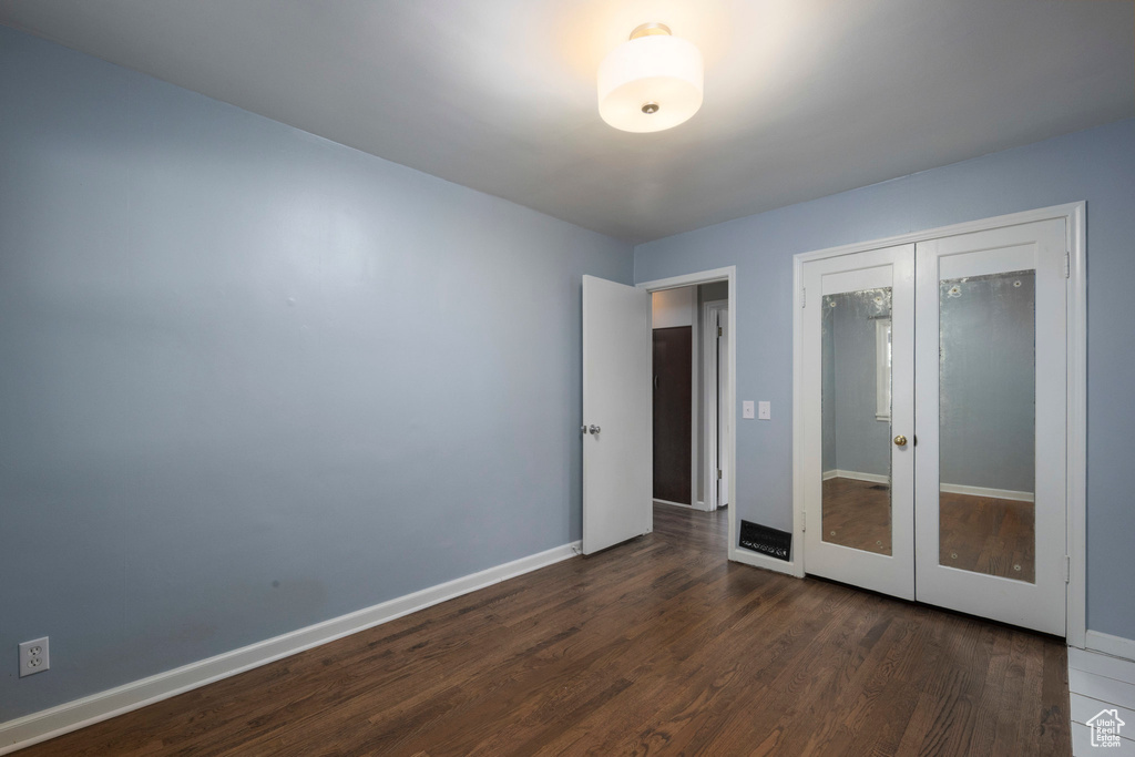 Unfurnished room with dark wood-style flooring, baseboards, and french doors