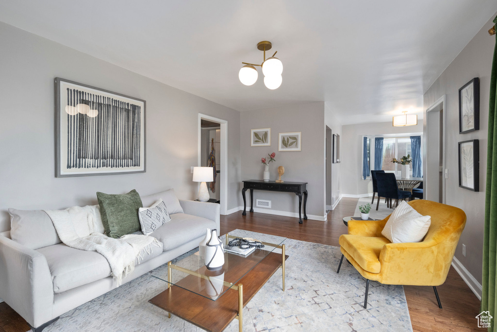 Living room with wood finished floors, a chandelier, and baseboards