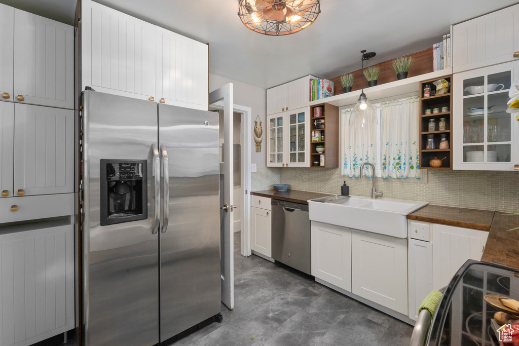 Kitchen with appliances with stainless steel finishes, a sink, open shelves, backsplash, and white cabinets