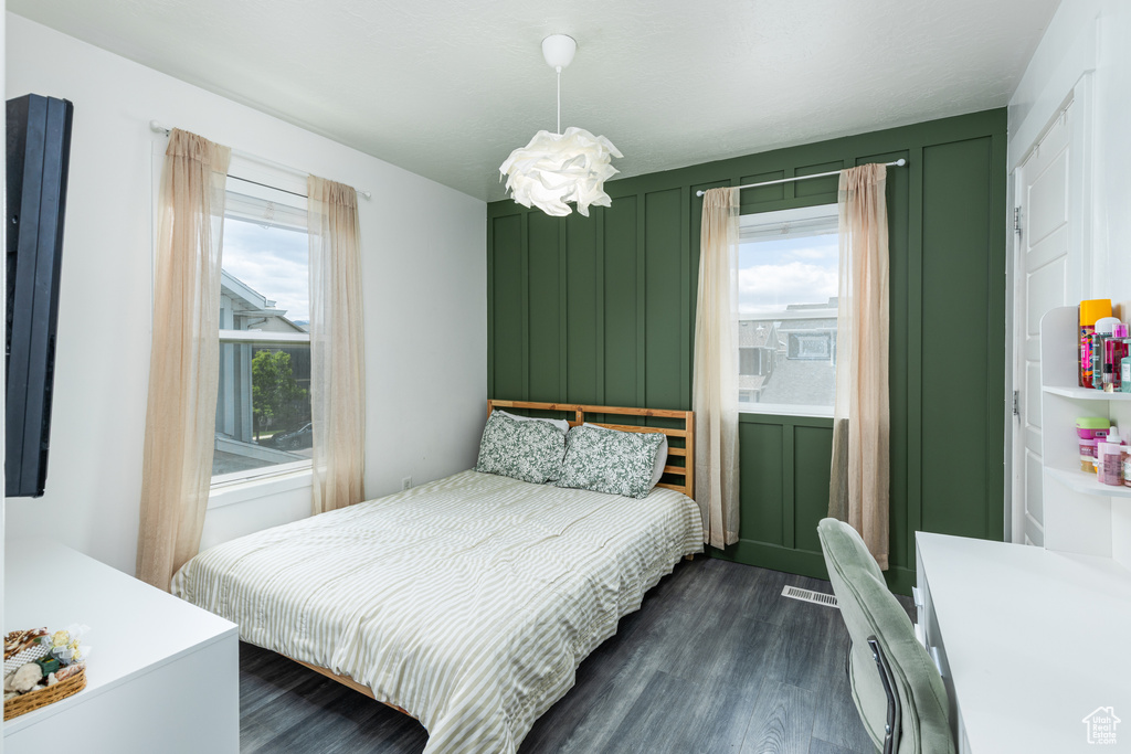 Bedroom with dark wood-style floors and a decorative wall