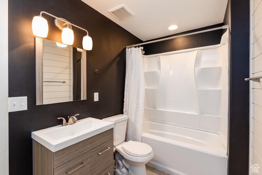 Bathroom with toilet, vanity, and shower / tub combo with curtain