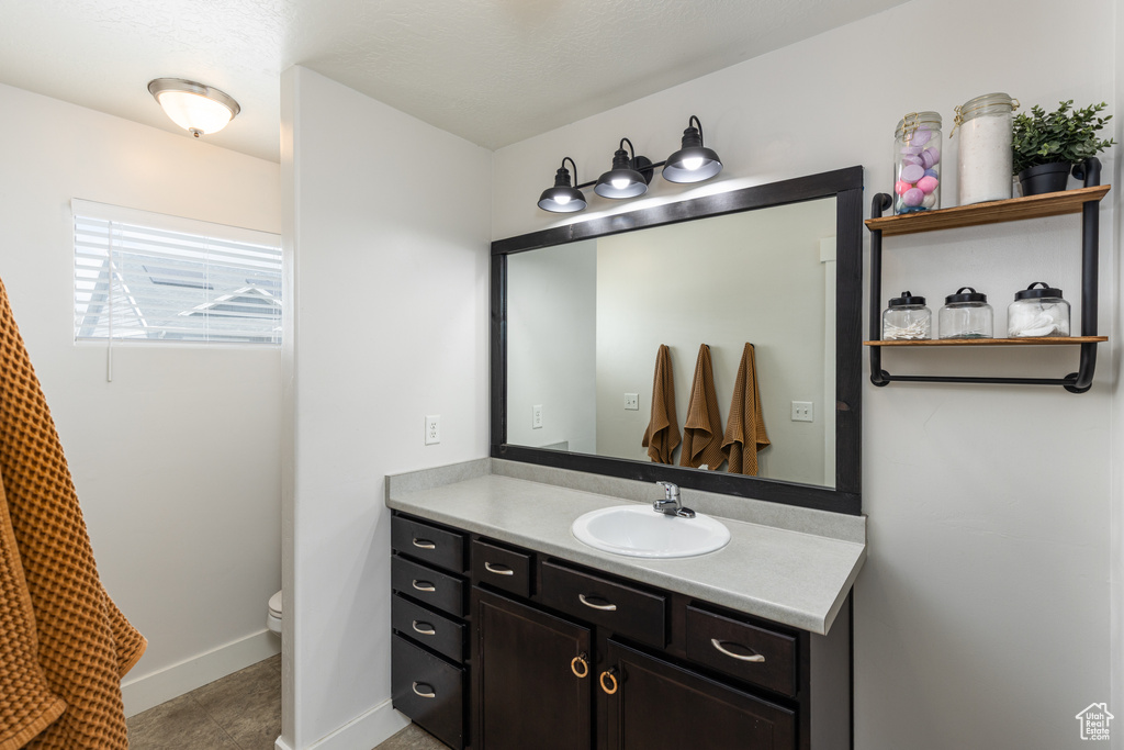 Bathroom with toilet, vanity, baseboards, and tile patterned flooring