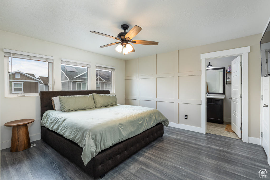 Bedroom with dark wood-style flooring, baseboards, a decorative wall, and ceiling fan