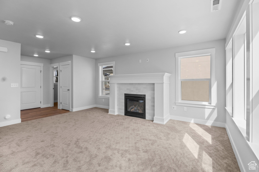 Unfurnished living room featuring carpet flooring, recessed lighting, a tiled fireplace, and baseboards