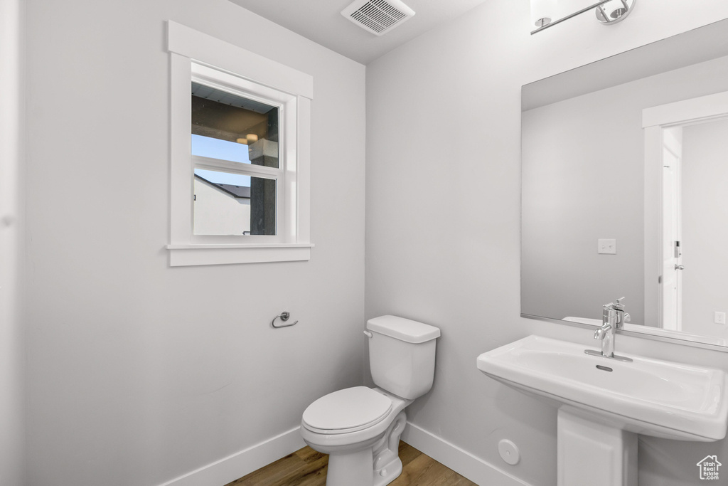 Bathroom with wood finished floors, baseboards, toilet, and a sink