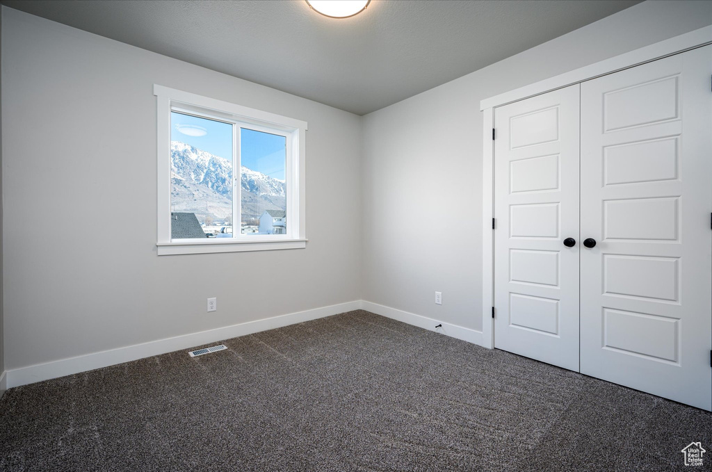 Unfurnished bedroom with dark colored carpet, baseboards, and a closet