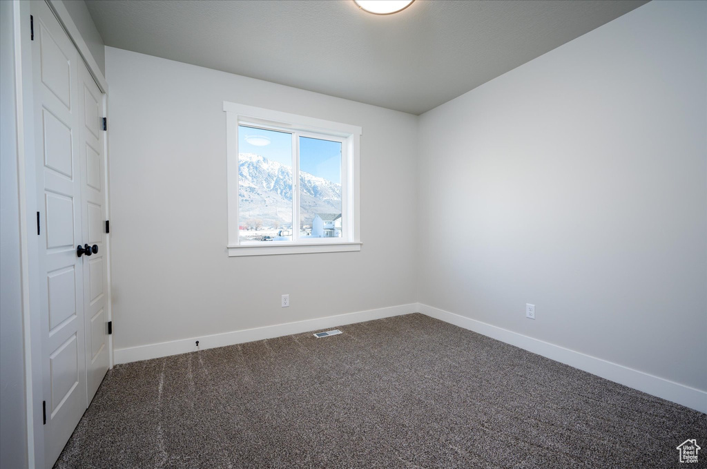 Unfurnished room featuring dark colored carpet and baseboards