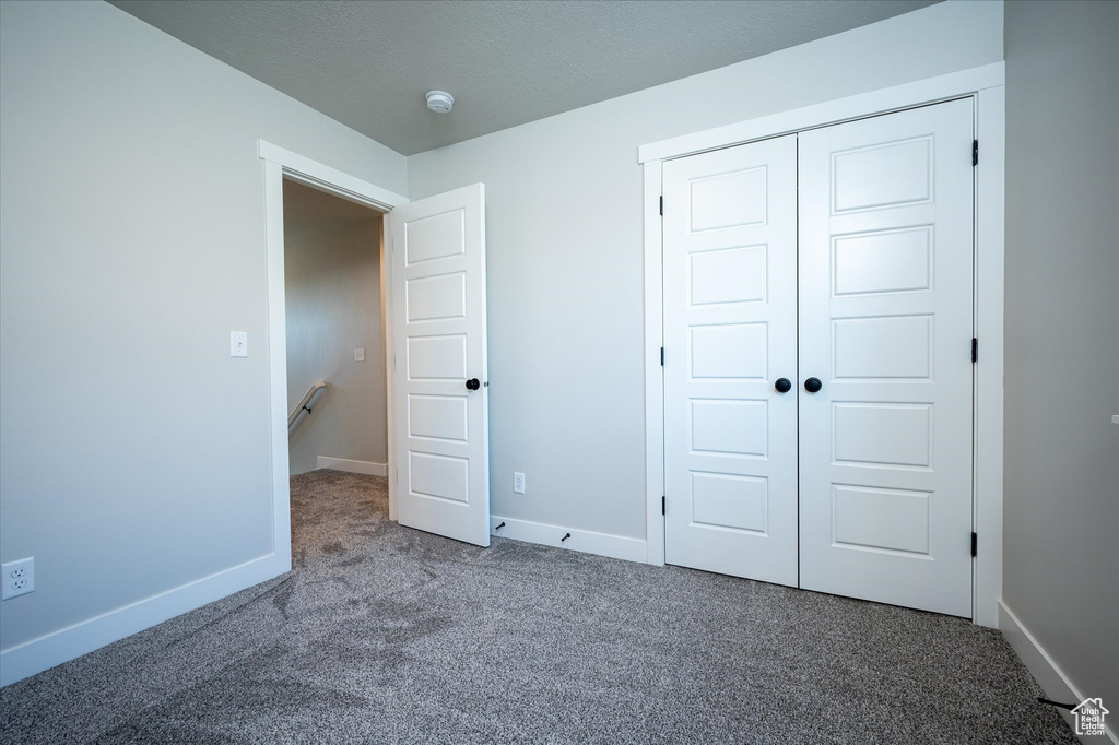 Unfurnished bedroom featuring carpet floors, a closet, and baseboards