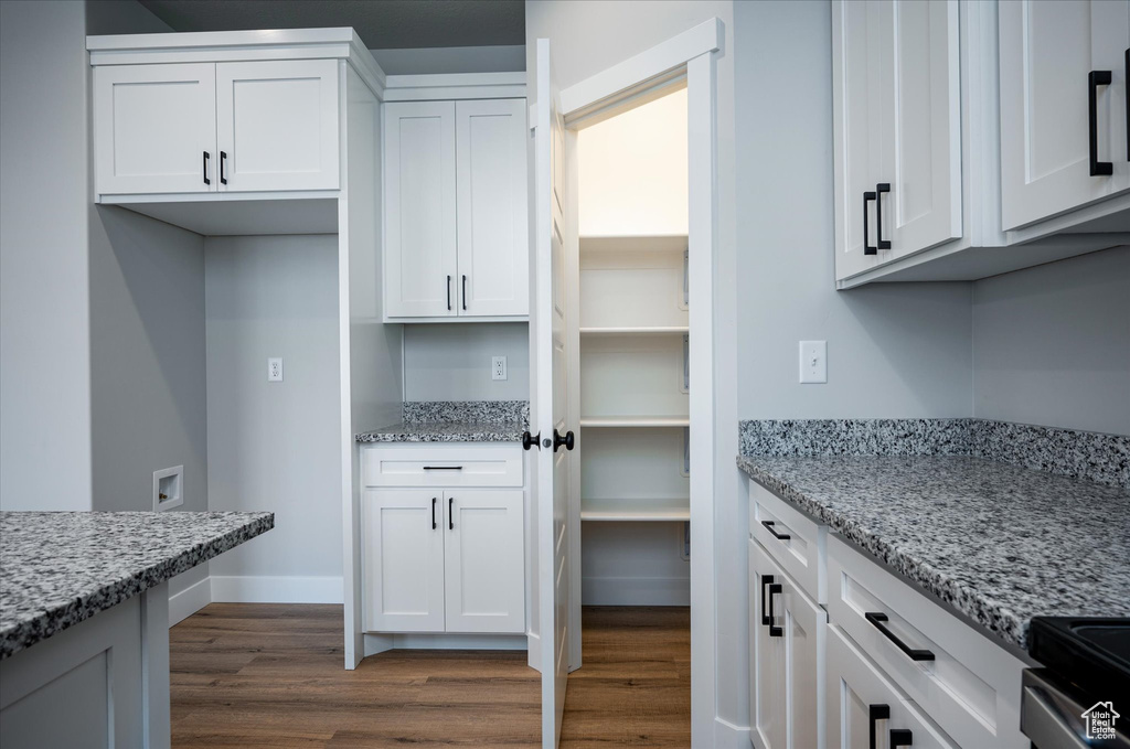 Kitchen with dark wood-style floors, white cabinets, and light stone countertops