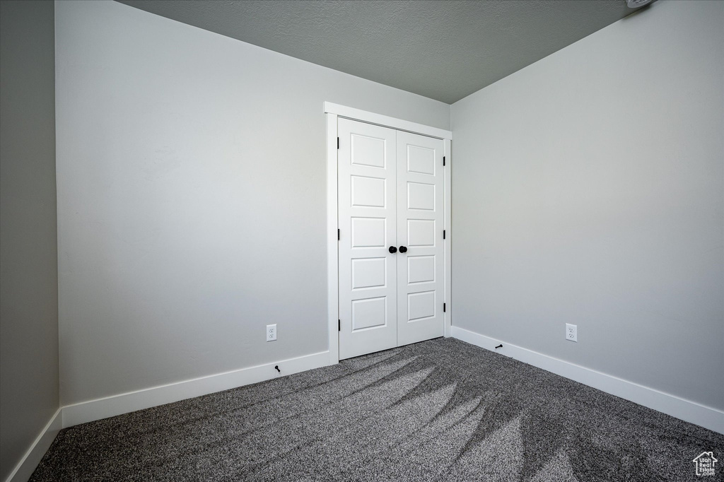 Unfurnished room featuring dark carpet and baseboards