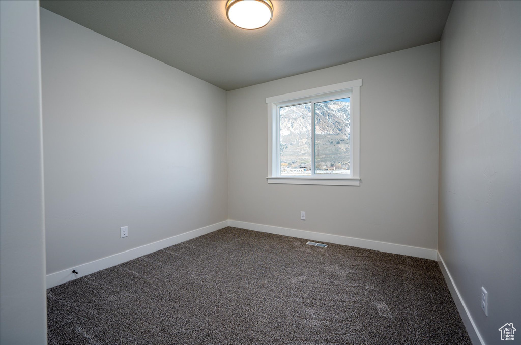 Unfurnished room with dark carpet and baseboards