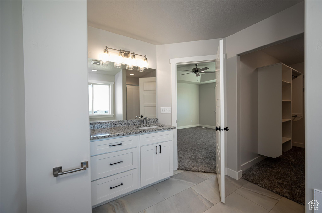 Full bathroom with ceiling fan, vanity, baseboards, and tile patterned flooring